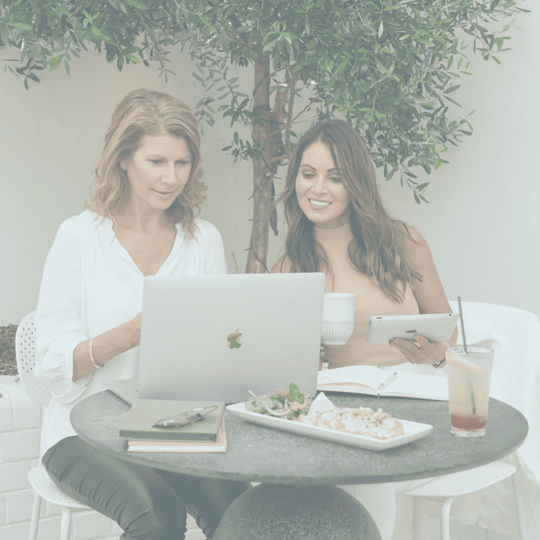 Two women sitting at a table, working as web designers on a laptop.
